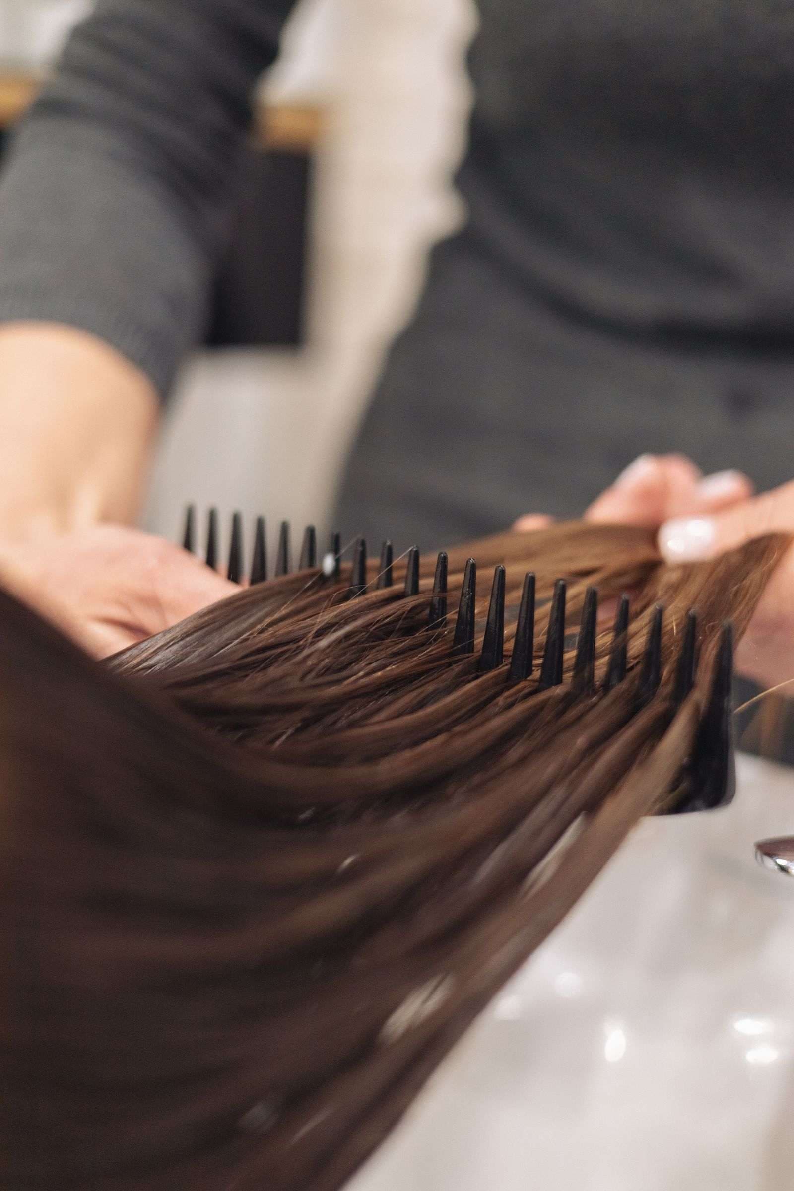 Stylist combing through sleek, smoothed hair during a keratin treatment at Page 3 Luxury Salon, Madurai